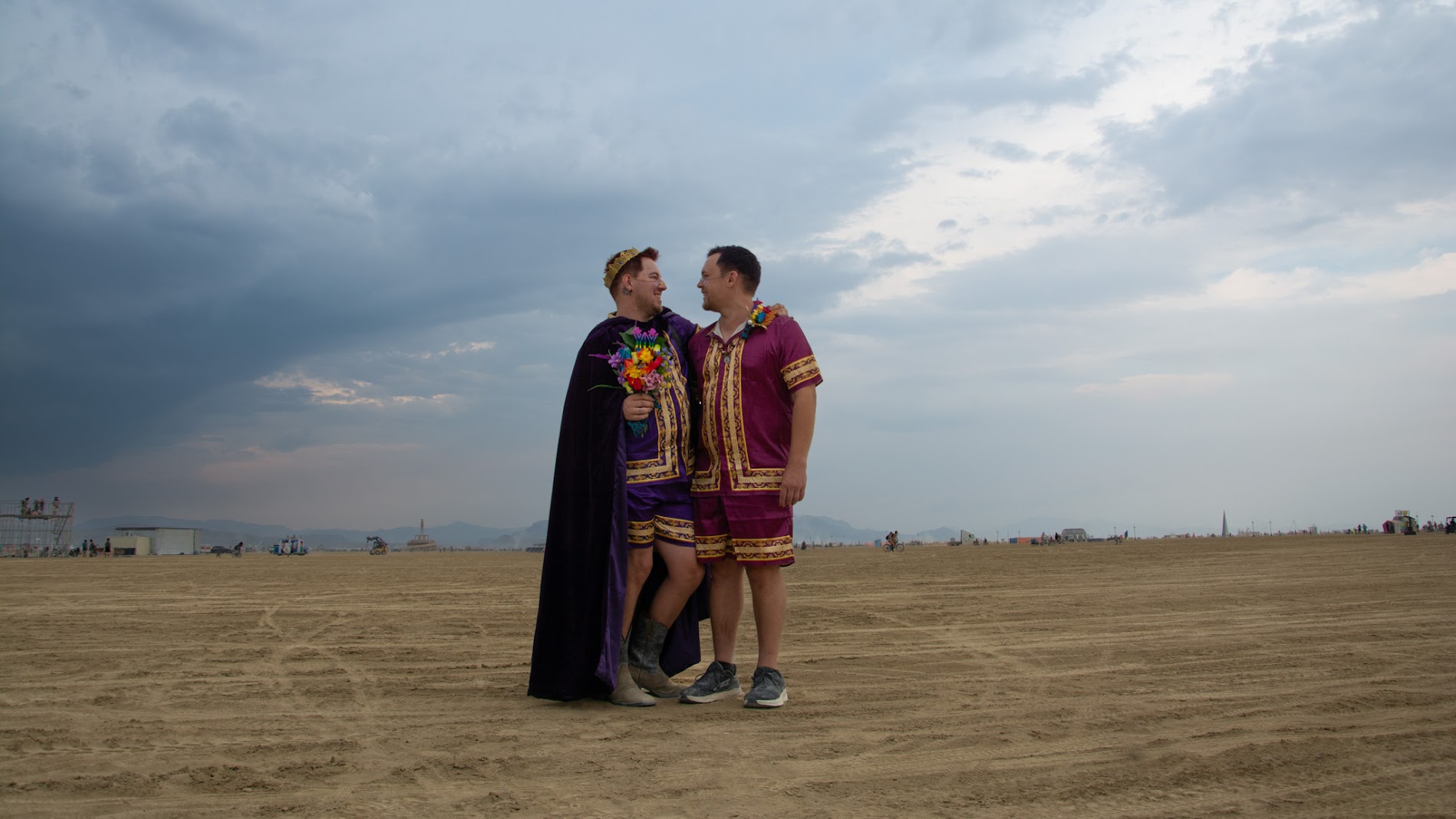 Dillon and Sideshow in ornate purple wedding attire standing together on the open playa