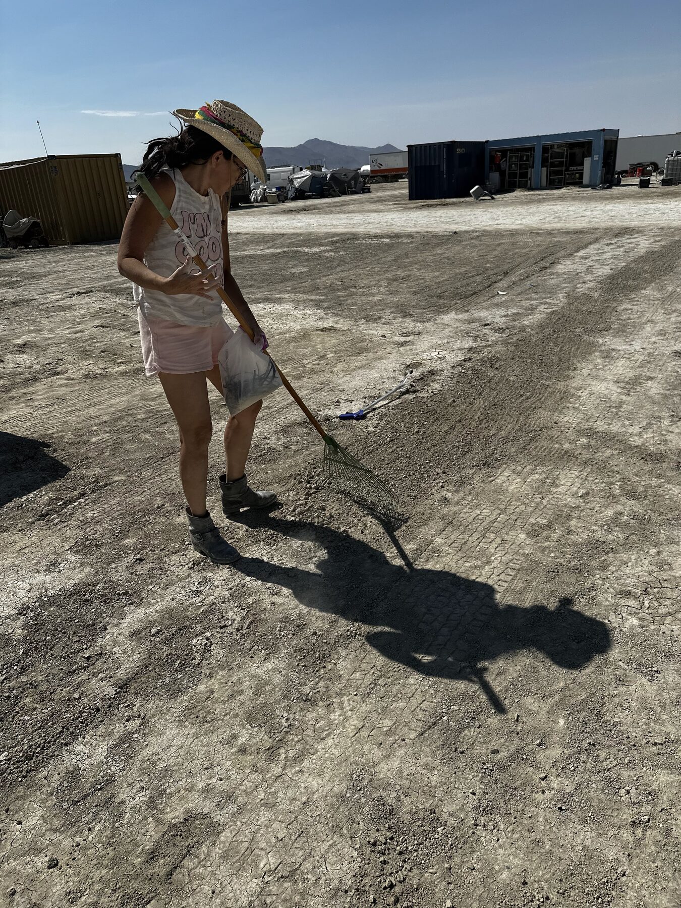 A camper raking the playa for MOOP in the afternoon sun