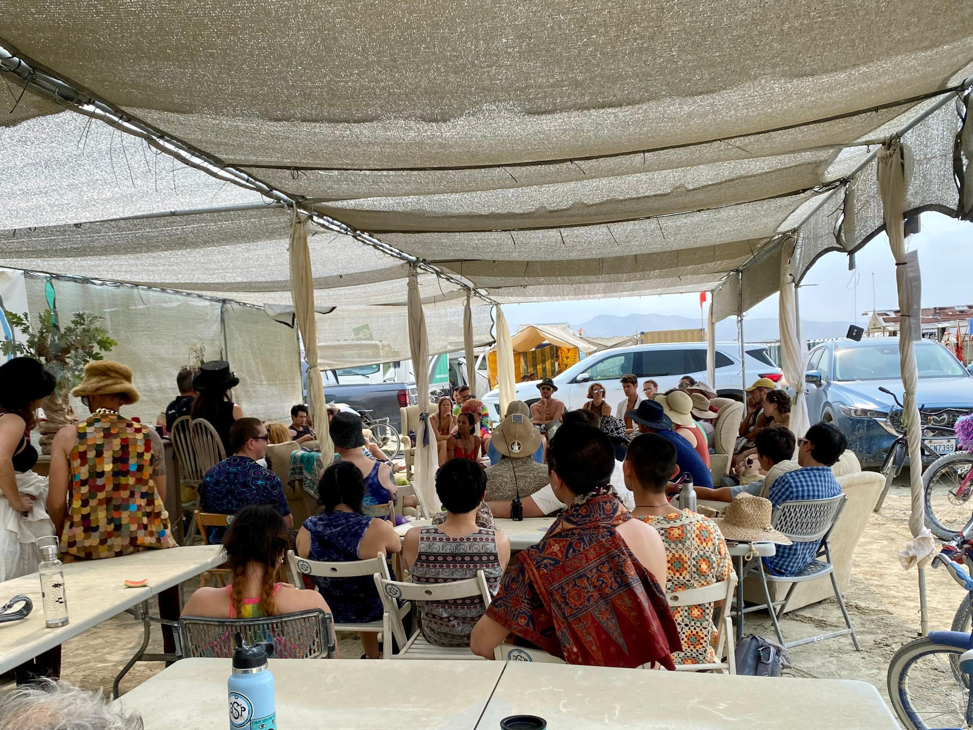 A large group gathered under the Vivarium shade structure for a camp talk